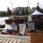 Tradycyjna Wiślana łódź płaskodenna ozdobiona zdjęciami z budowy stoi przy bulwarze na festiwalu Loary w Orleanie