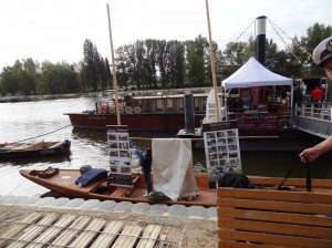 Tradycyjna Wiślana łódź płaskodenna ozdobiona zdjęciami z budowy stoi przy bulwarze na festiwalu Loary w Orleanie